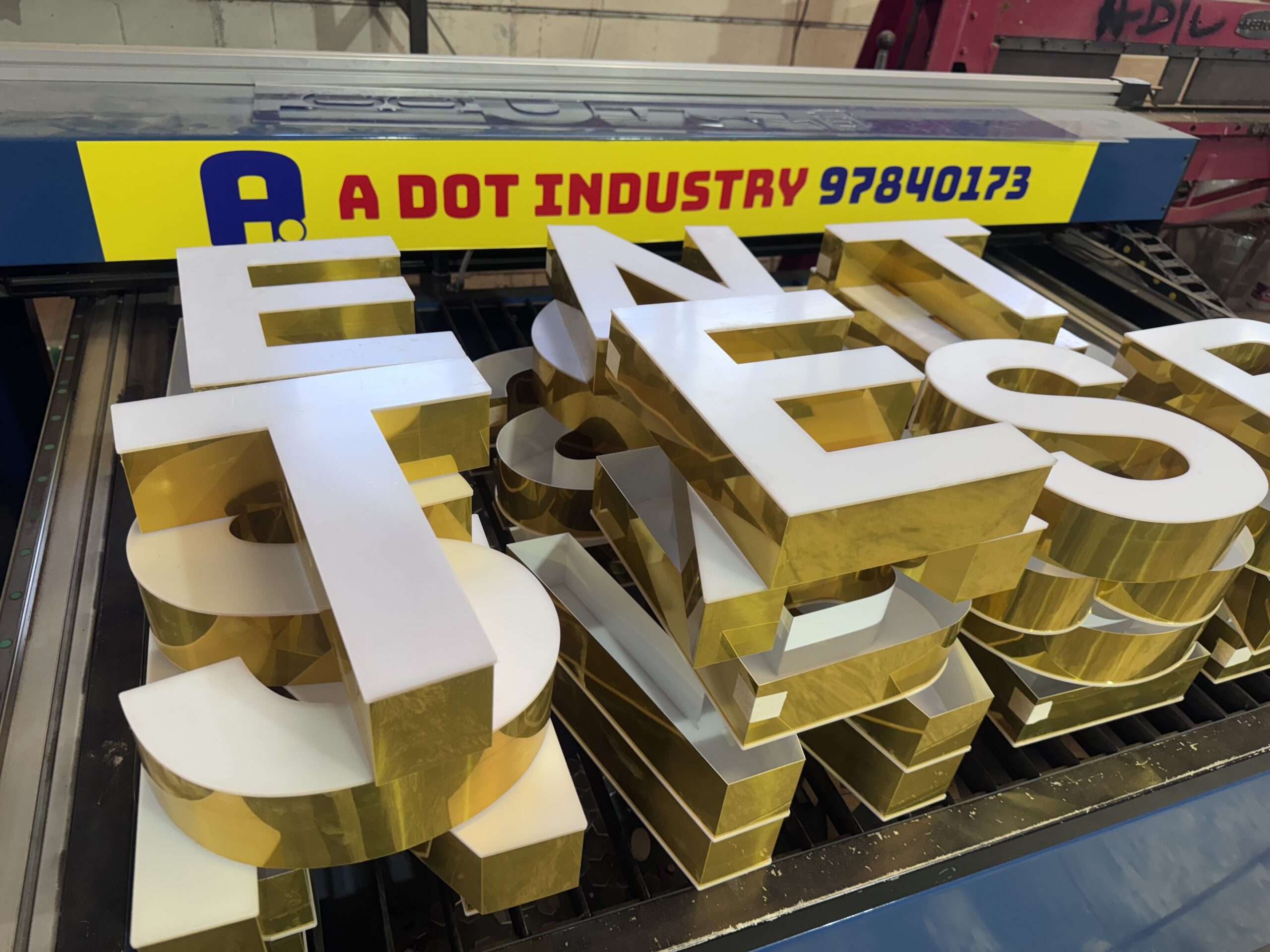 Gold and white 3D letters stacked in a workshop.