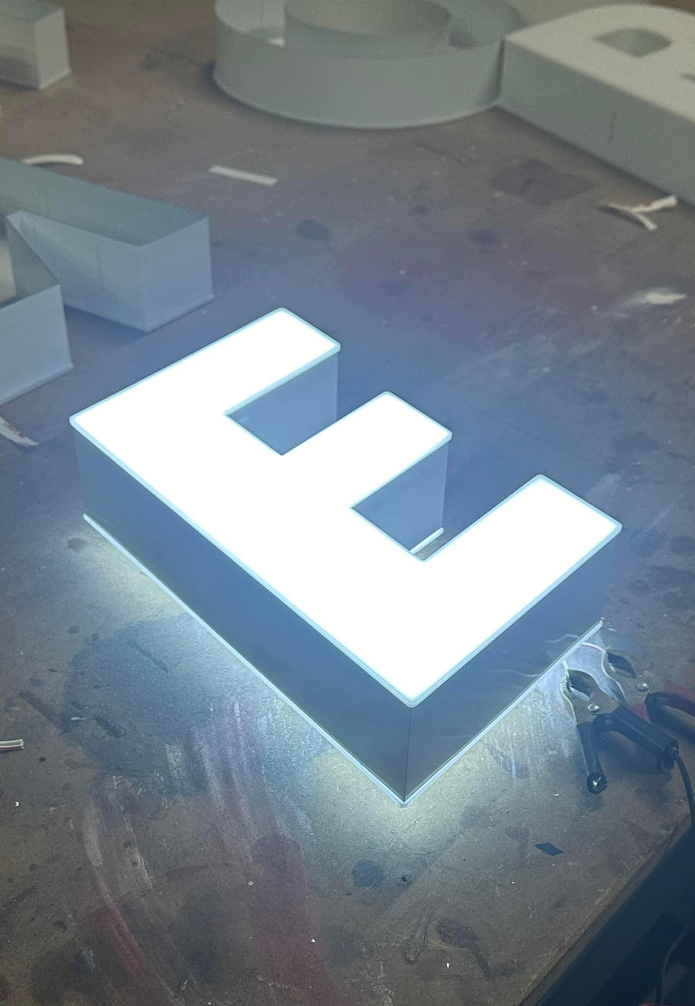Illuminated 3D letter E on a workshop table