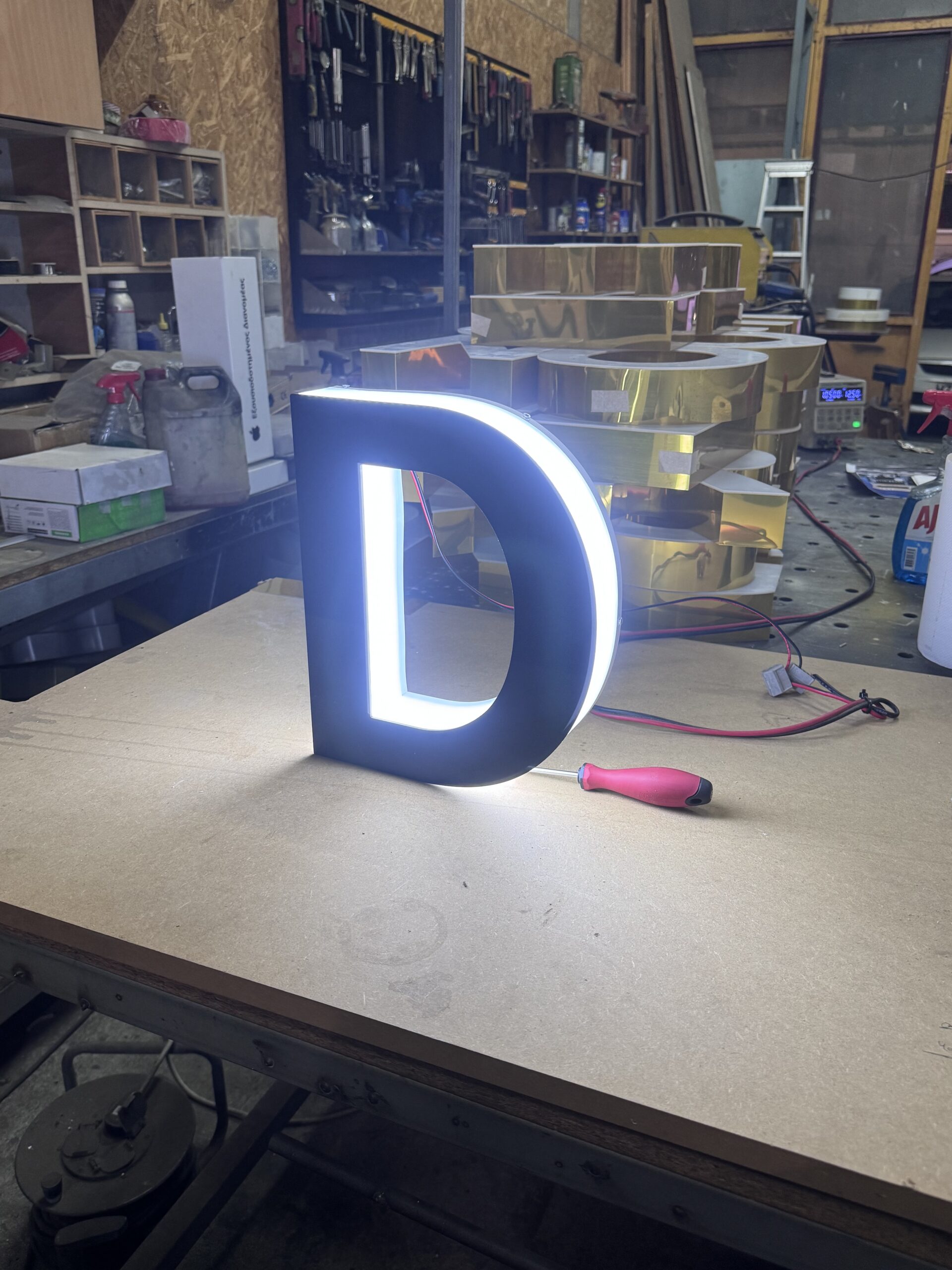 Illuminated 3D letter D on a workshop table