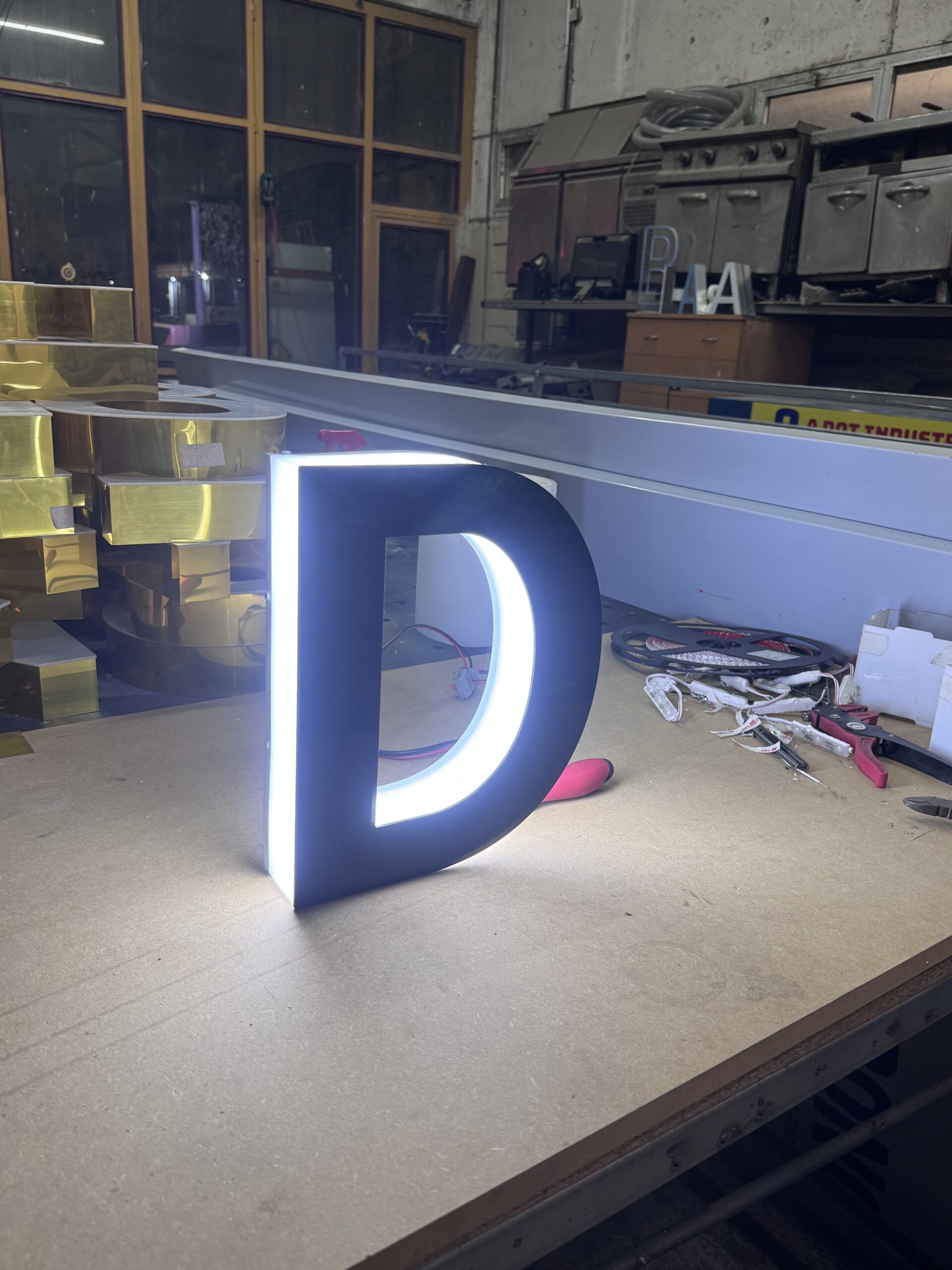 Illuminated 3D letter D on a table in a workshop.