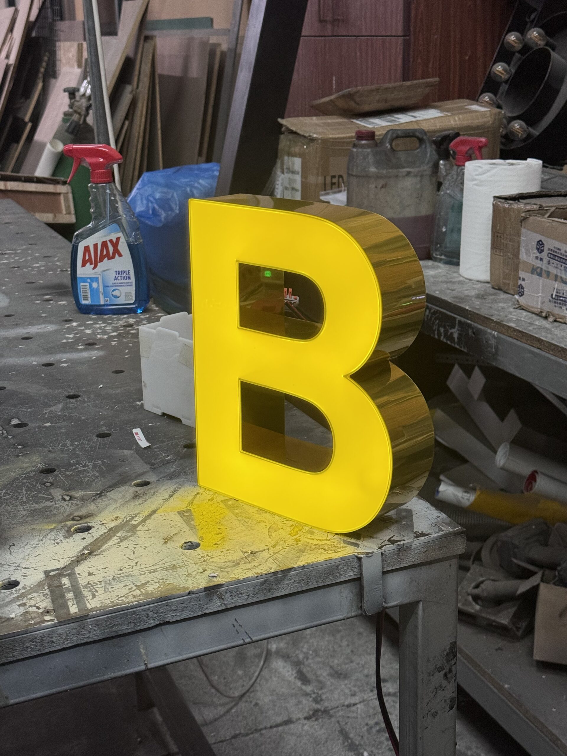Yellow illuminated 3D letter B on workshop table