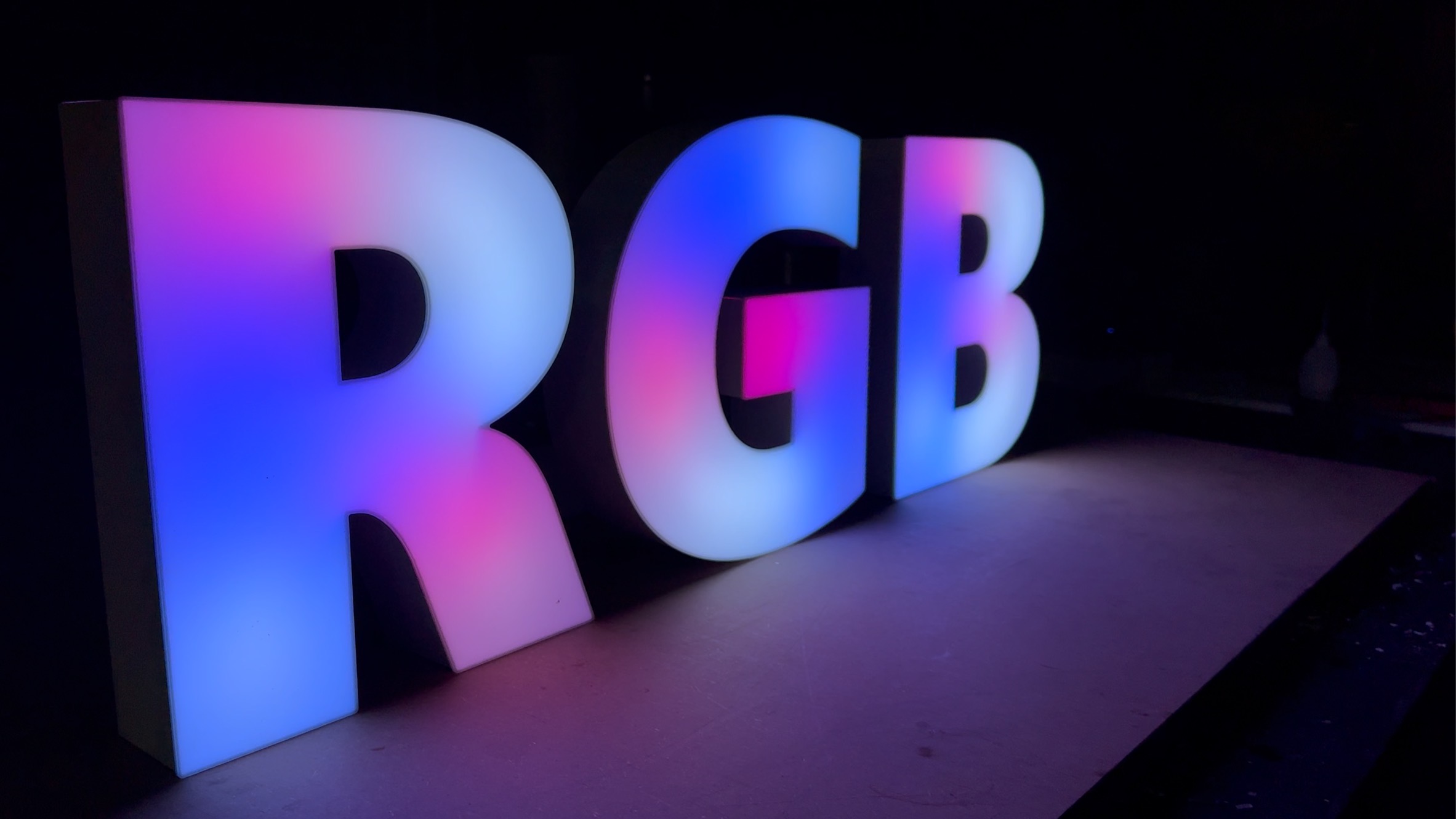 Illuminated RGB 3D letters displaying colors in a dark setting