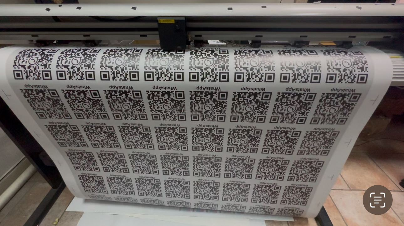 Sheet of custom QR codes being printed in a workshop.